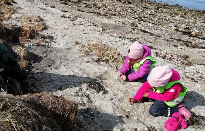 To barn fra Tomasjordneset barnehage leker i fjæra