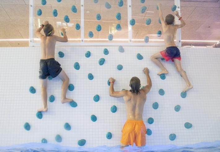 Barn som klatrer på vegg ved svømmebasseng