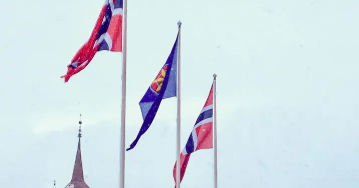 To norske og et kvensk flagg vaier utenfor Tromsø rådhus i mars 2019