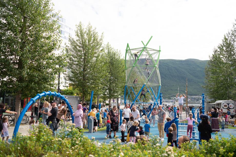 Oversiktsbilde som viser Strandtorget lekeplass og barn som leker under den offisielle åpningen av lekeplassen.