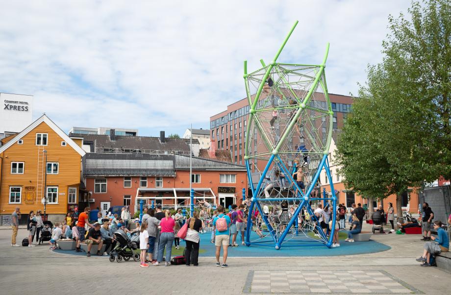 Oversiktsbilde som viser Strandtorget lekeplass og barn som leker under den offisielle åpningen av lekeplassen.