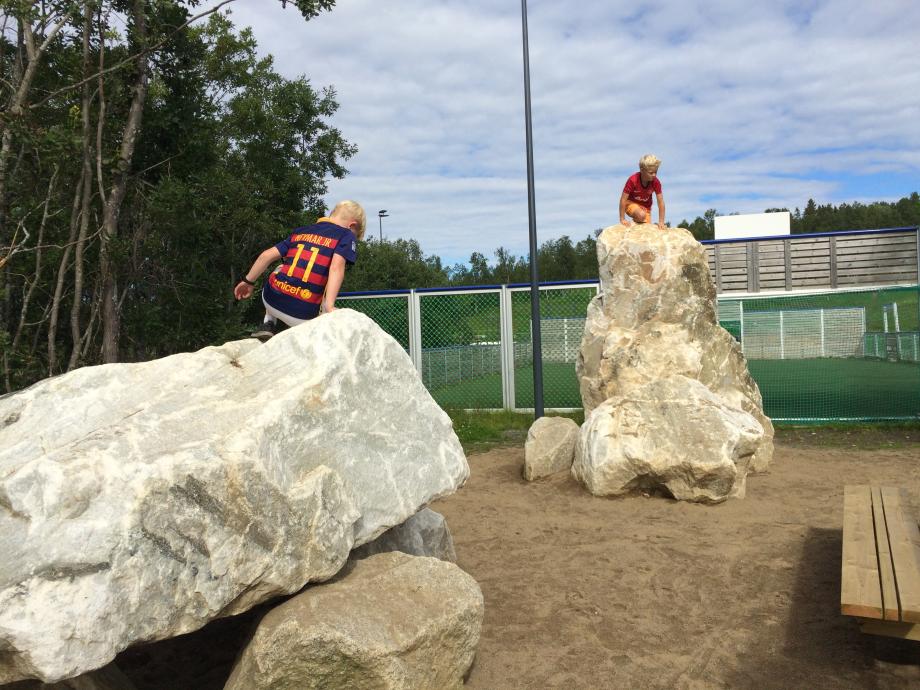 To gutt klatrer på store steiner i Charlottenlund aktivitets- og friluftspark