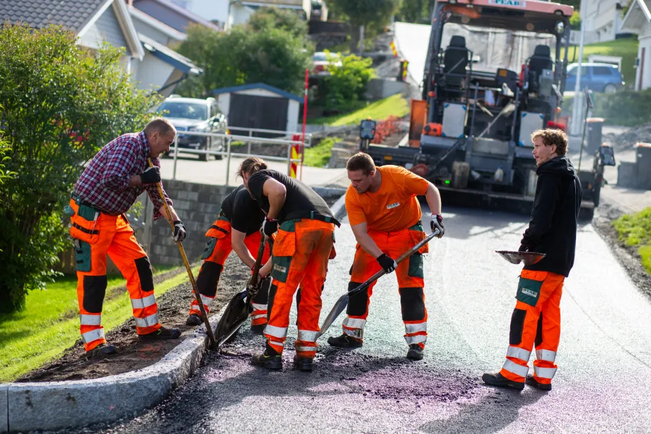 Fem arbeidere legger asfalt i vei