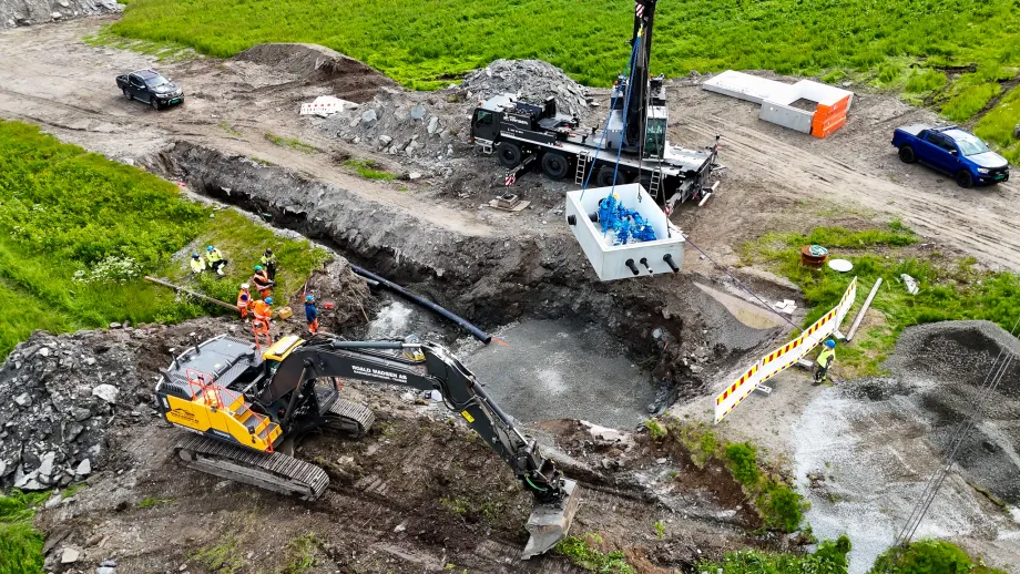 Dronefoto av kum som l&oslash;ftes ned i gr&oslash;ft av heisekran
