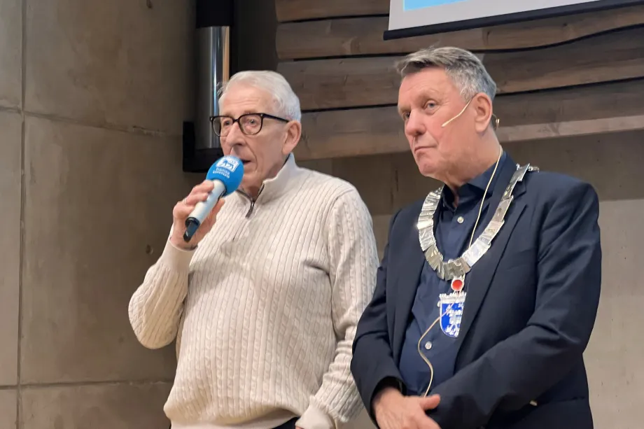 Idrettens heders- og frivillighetspris for 2025 til Hans-Tore &laquo;Boa&raquo; Hanssen. Hanssen holder mikrofon mot munnen. Ordf&oslash;reren st&aring;r ved siden av.