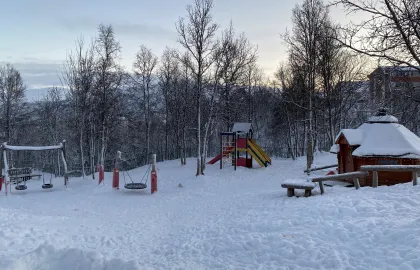 Uteområde med lavvo, husker og leketårn en fin vinterdag med snø og blå himmel