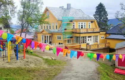 Barnehagen dekorert med hengende fargerike vimpler utenfor barnehagen en sommerdag