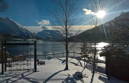 Uteområdet i Lakselvbukt barnehage en strålende vinterdag med sol, hav og fjell