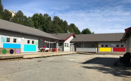 Slettaelva barnehage sett utenfra en solrik sommerdag med bl&aring; himmel og gr&oslash;nn skog