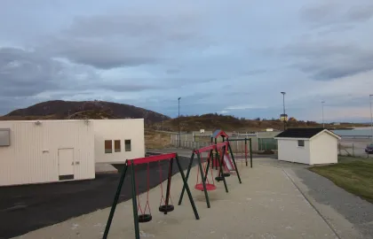 Sommarøy barnehage uteområde med husker og sandkasse en sommerdag