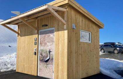 Slik ser et av Tromsø kommunes friluftstoalett ut. Her er toalettdøren utsmykket med fotografi av en fuggel.