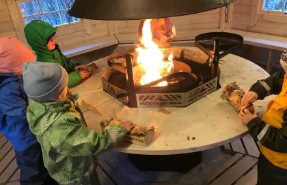 Fire barn som legger ved på bålet i grillhytta ved Norlandia Polarmåsen barnehage