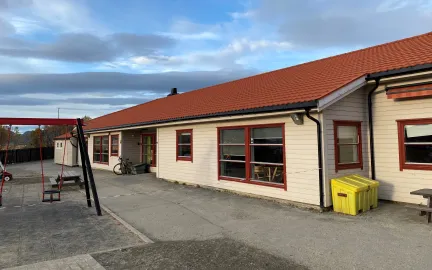 Toftveien barnehage sett utenfra med lekeapparater og sandkasse