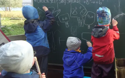  Tre barn tegner p&aring; tavle ute ved Tusseladden friluftsbarnehage