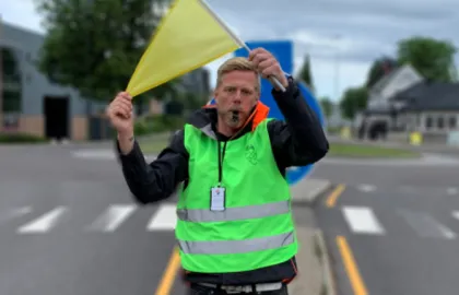 Mannlig løypevakt i refleksvest som viser et gult flagg.