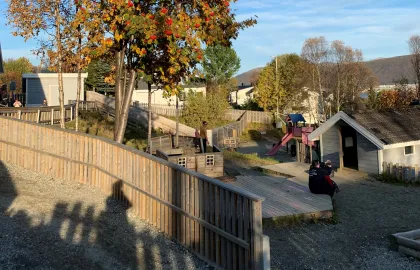 Gimle studentbarnehage med lekeområde sett utenfra en sommerdag med blå himmel