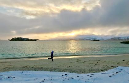 Gutt løper på strand vinter