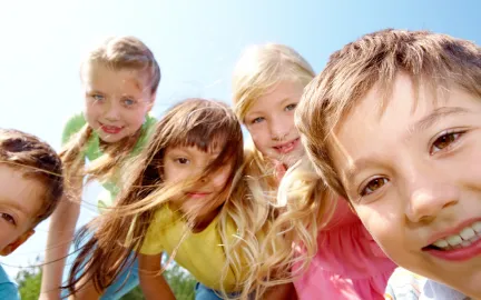 Fem glade barn som leker ute en fin sommerdag