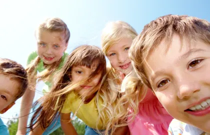 Fem glade barn som leker ute en fin sommerdag