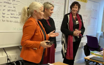 Rektor ved voksenoppl&aelig;ringen Lena Steinsvik Hansen, arbeids- og inkluderingsminister Marte Mj&oslash;s Persen og spr&aring;kl&aelig;rer Marit N&aelig;svoll foran spr&aring;kklassen st&aring;r fremst i klasserommet under norskoppl&aelig;ringen for innvandrere