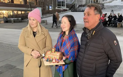 Kristina Torbergsen, Maja Kristine J&aring;ma og Gunnar Wilhelmsen p&aring; Stortorget. J&aring;ma, i midten, holder et pepperkakehus p&aring;skrevet Samisk hus.
