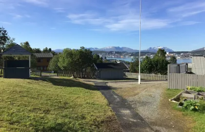 Uteområde Kroken barnehage med utsikt mot Tromsøya en solrik sommerdag