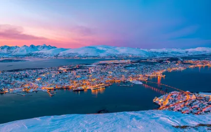 Panoramabilde av et sn&oslash;kledt Troms&oslash;ya tatt fra fjellheisen i Tromsdalen.