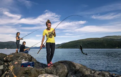 Tre kvinner fisker på Hella midtsommers Tre kvinner fisker ved havkanten på Hella midtsommers