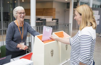 Kvinne som legger stemmeseddel i valgurne