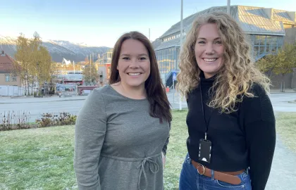 Sigrid Mogård-Jansen, til venstre, og Helga Bårdsdatter Kristiansen fra Tromsø kommune står på plenen utenfor rådhuset, og smiler mot kamera.