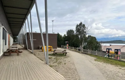 Uteområde med benker og klatretårn en sen sommerdag med skyer og blå himmel.