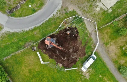 Dronebilde av gravemaskin og grøft i skolegård