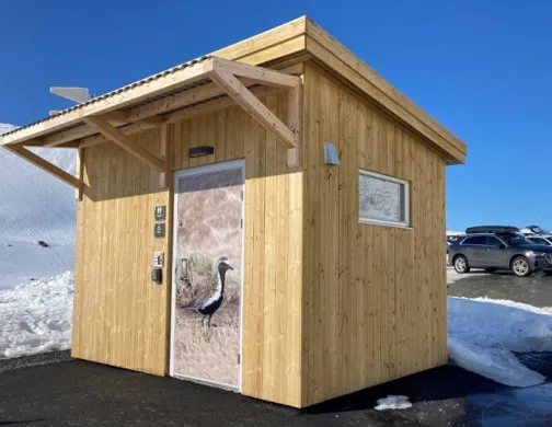 Slik ser et av Troms&oslash; kommunes friluftstoalett ut. Her er toalettd&oslash;ren utsmykket med fotografi av en fuggel.