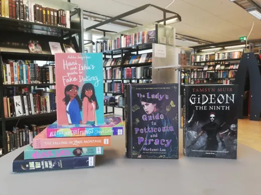 Tre b&oslash;ker oppstilt med fronten mot kamera, fire b&oslash;ker ligger p&aring; bordet ved siden. Foto.