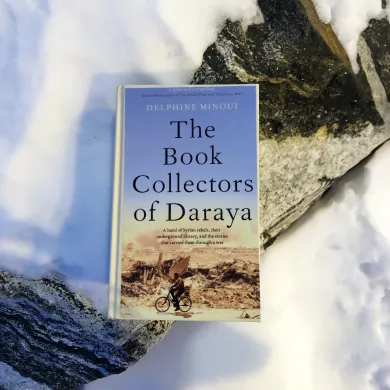 Bok ligger p&aring; en stein med fronten mot kamera. Det er sn&oslash; p&aring; bakken rundt boka. Foto.