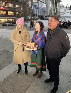 Kristina Torbergsen, Maja Kristine J&aring;ma og Gunnar Wilhelmsen p&aring; Stortorget. J&aring;ma, i midten, holder et pepperkakehus p&aring;skrevet Samisk hus.