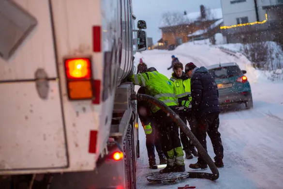 Fire arbeidere st&aring;r over &aring;pen kum midt i gate i Troms&oslash;.