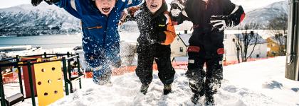 Tre glde barn hopper i snøen i Gyllenvang barnehage 