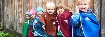 Seks barn ved gjerde med fargerike luhkka i Samisk barnehage 