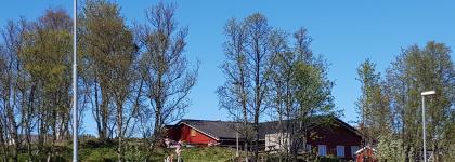 Ameliahaugen barnehage sett utenfra en fin sommerdag med trær og blå himmel